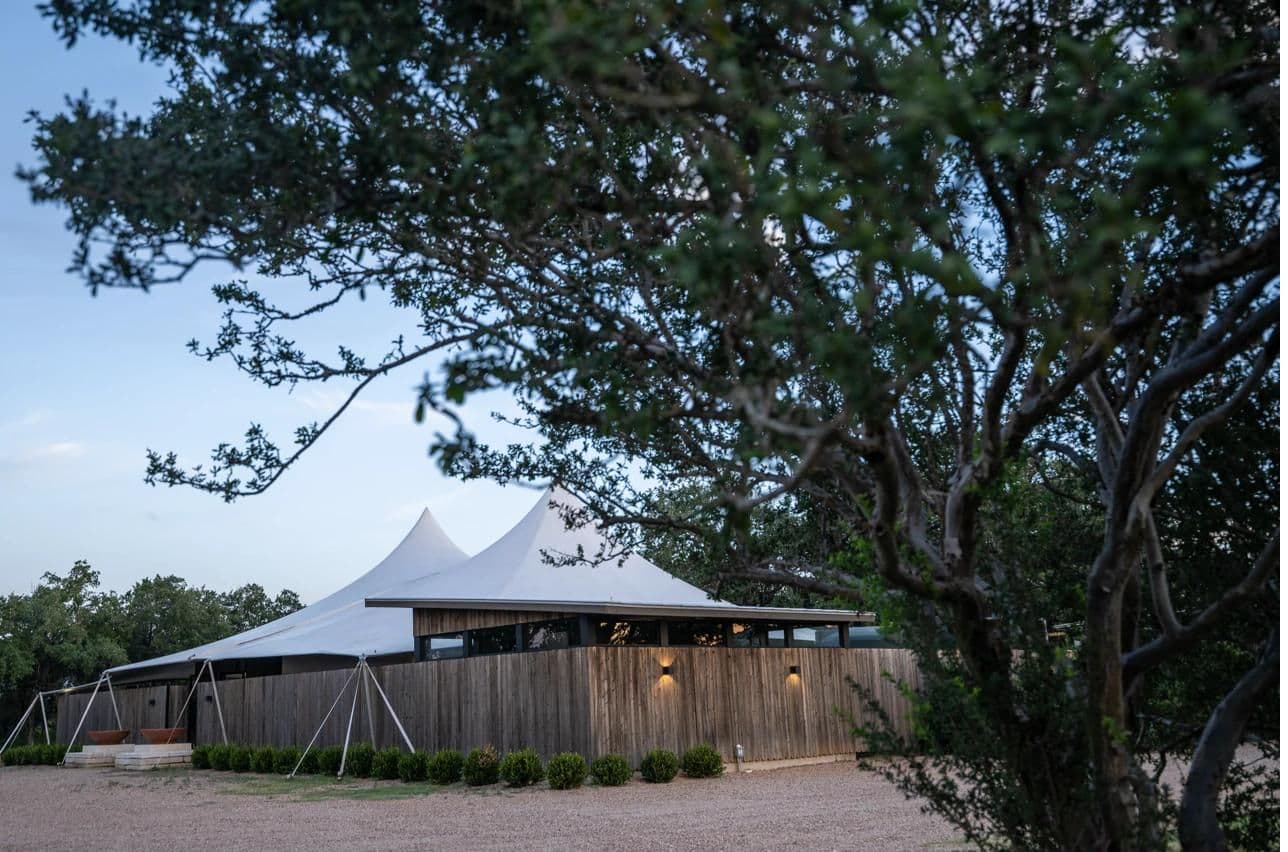 The Pavilion exterior with tent peaks beneath oak trees